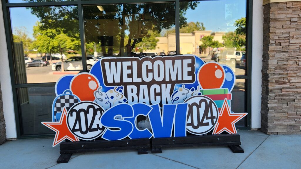 Colorful sign in front of mirrored window building says “Welcome Back SCVi 2023-2024.