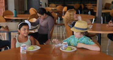 SCVi students sit at a table eating lunch in a modern cafe-like setting.