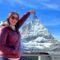 Santa Clarita Valley International (SCVi) School alum Emma Hild stands in front of a mountain with her arm raised making it look like she’s touching the peak.