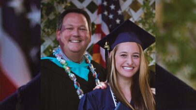Santa Clarita Valley International (SCVi) student Paige Guarino in blue graduation cap and gown poses with SCVi School Director Matt Watson wearing black gown with turquoise accents and candy lei.
