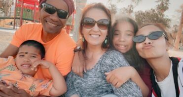 Santa Clarita Valley International (SCVi) student Elise Martinez’s family sits outside and smiles for the camera, one child sitting on an adult’s lap and everyone else lining up.